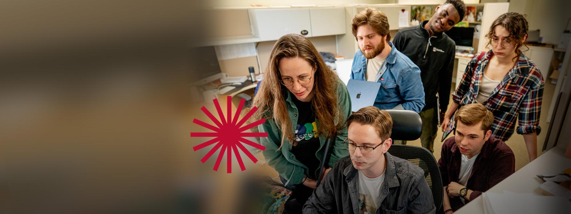 A group of six graduate students are sitting and standing in a physics classroom,concentrating a screen.
